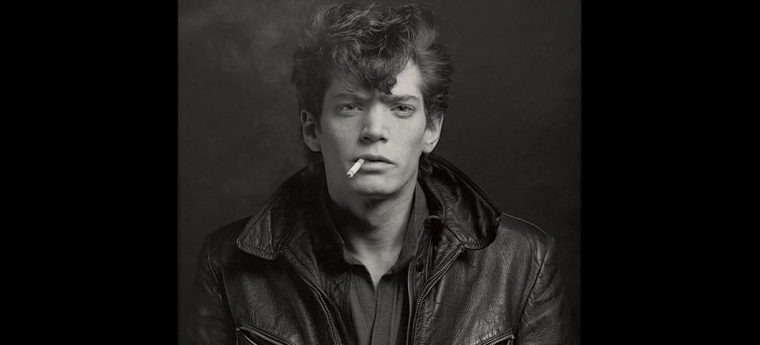 black-and-white photograph of Robert Mapplethorpe smoking a cigarette and wearing a black leather jacket , Self Portrait, 1980